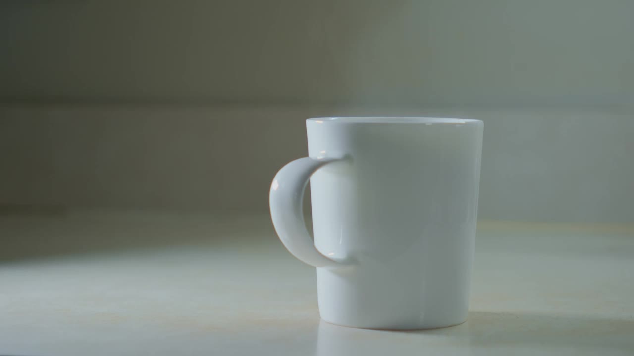 一只手从桌上拿起一个装着咖啡的白色杯子视频下载