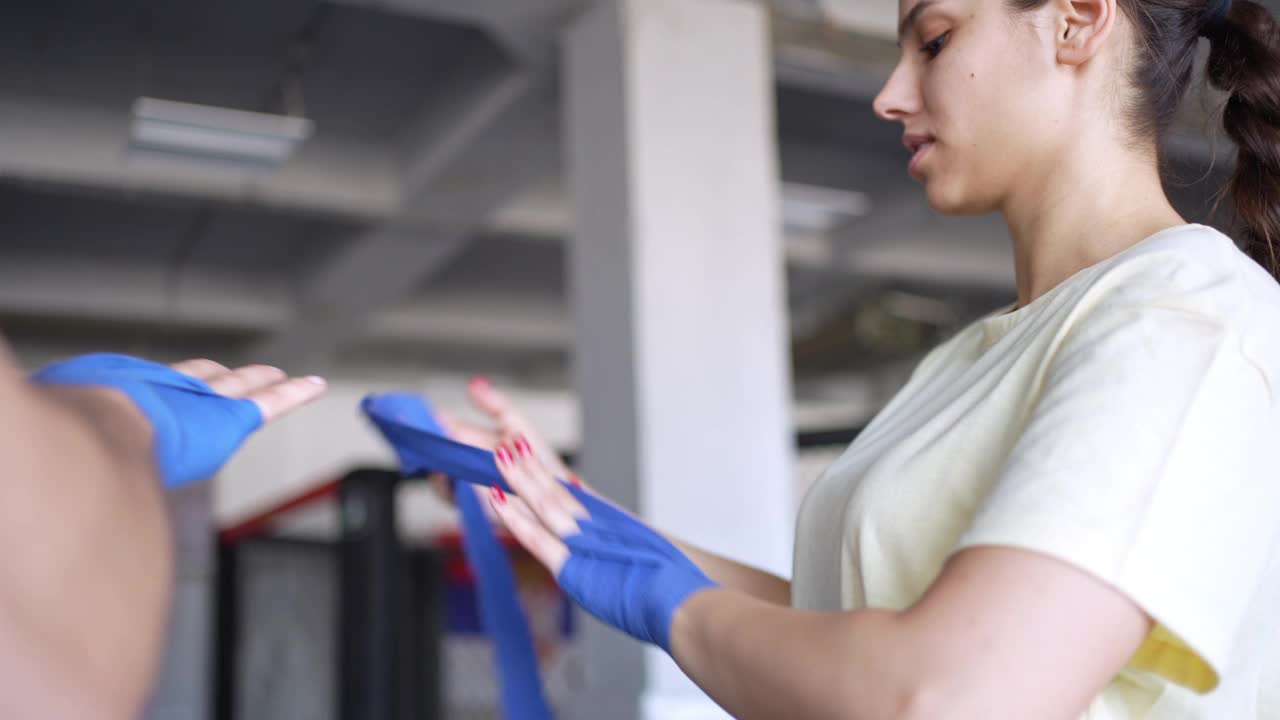 年轻女子用绷带包扎手和手腕，准备进行拳击训练视频下载