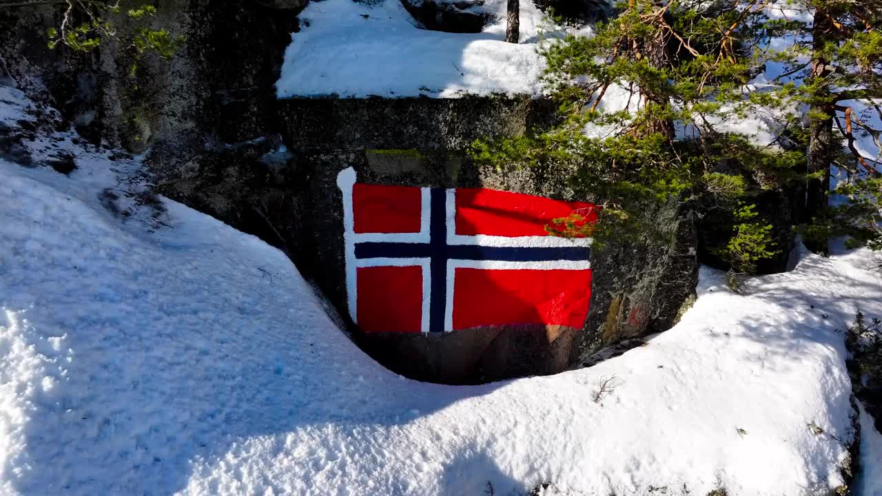 在挪威奥普兰的埃特尼达尔，积雪覆盖的山坡上，无人机拉出了挪威国旗视频素材