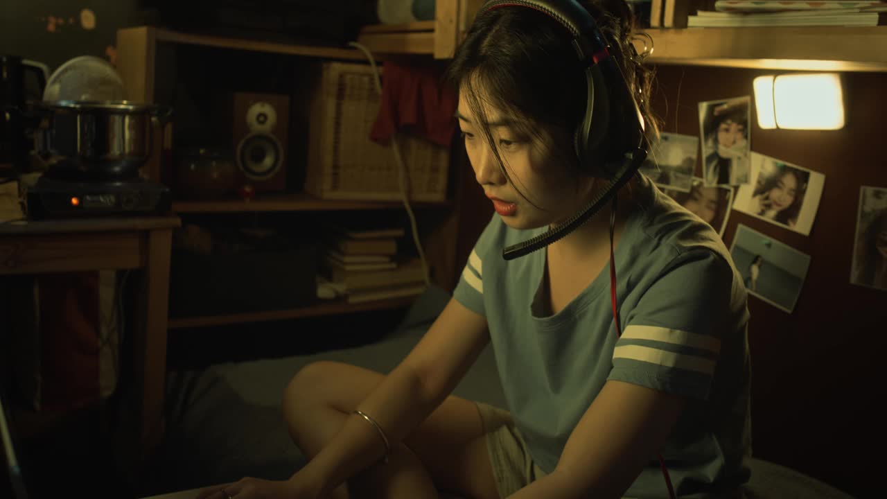 欢快的亚洲女孩戴着耳机在Shoebox Flat玩射击游戏视频下载