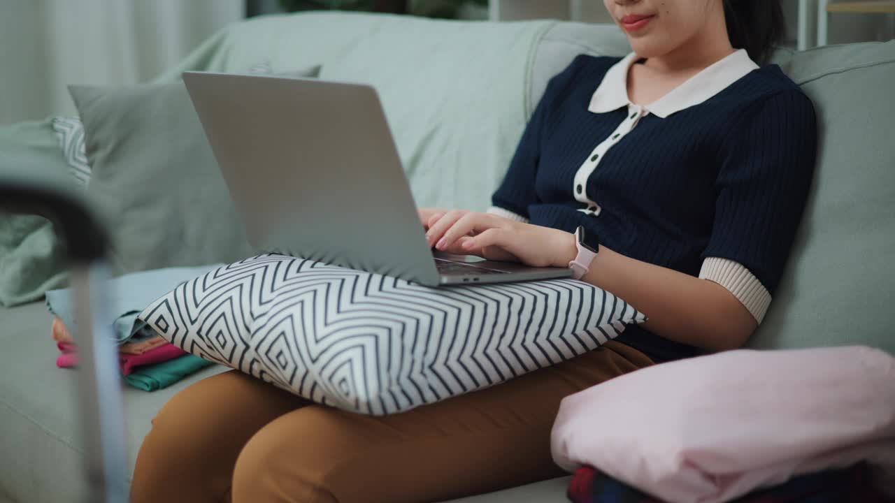 旅行计划。年轻女子在家里用笔记本电脑上网预订度假。视频下载