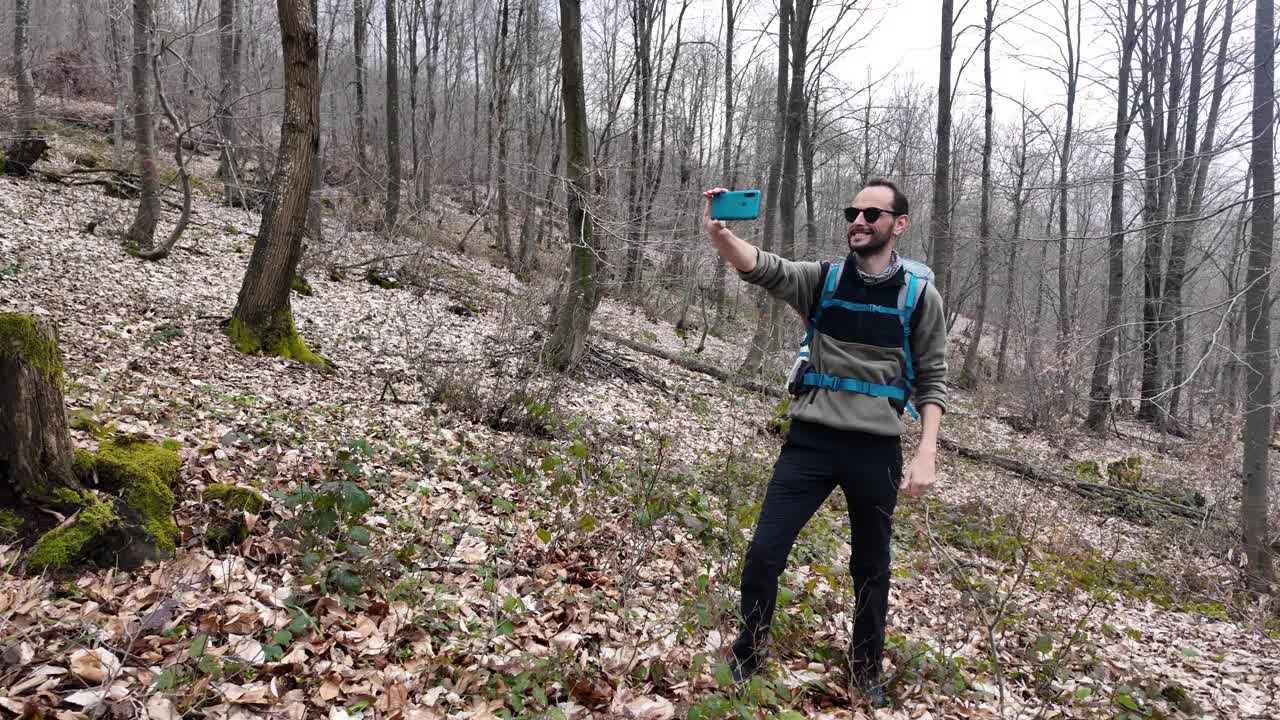 独自徒步旅行的男性在森林里自拍，背着背包打视频电话。视频下载