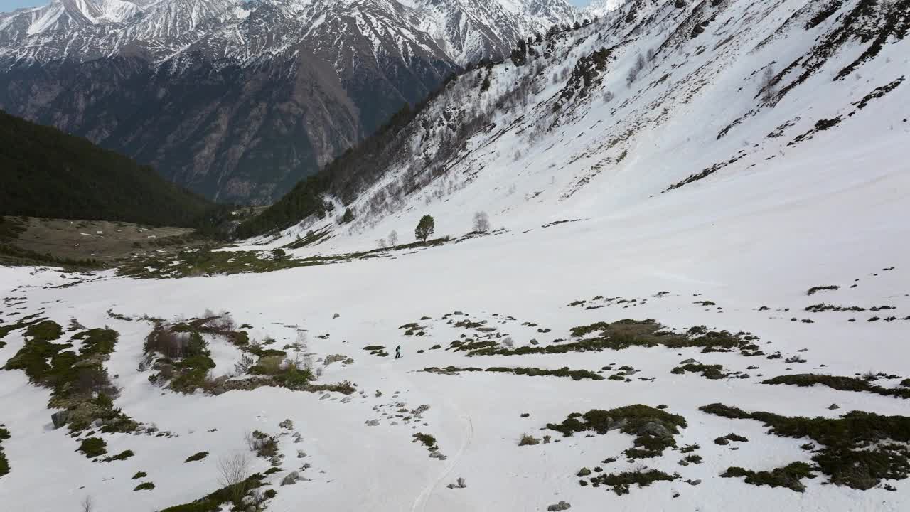 鸟瞰运动员滑雪自由骑在山坡上野外极限运动休闲冬季景观。一名男子在春季自由骑行时的残雪上放松视频下载