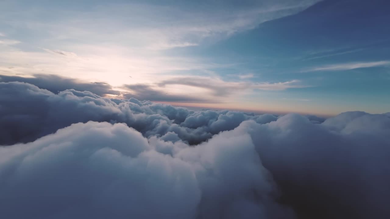 在云层之间飞行，以第一人称视角观看飞机在日落时分的飞行。云集群间的规划。鸟瞰图视频下载