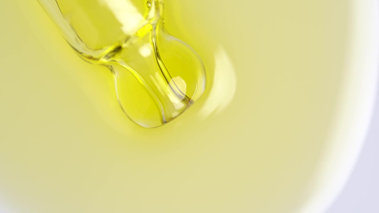 液体液体黄色油，凝胶或血清在白色的表面。用带有气泡的橙色化妆品液体移液器，微距镜头。视频下载