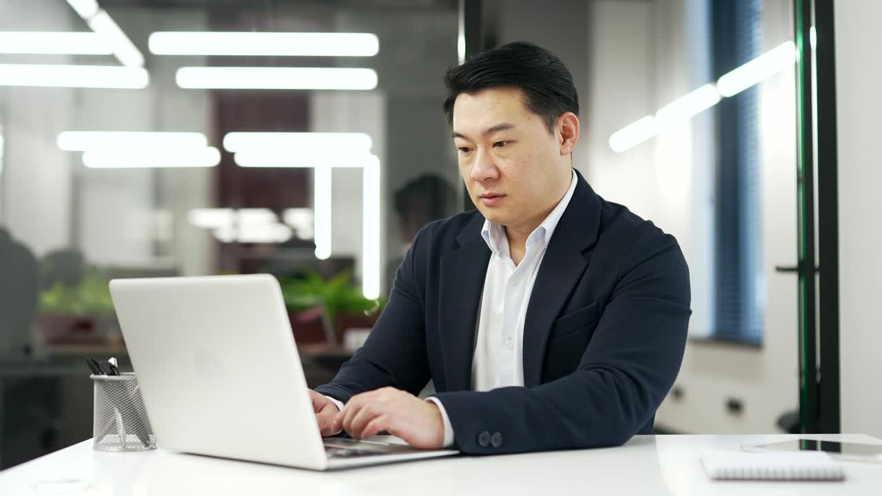 亚洲商人在办公室工作时，坐在办公桌前用笔记本电脑工作，患有恶心，想呕吐。视频下载