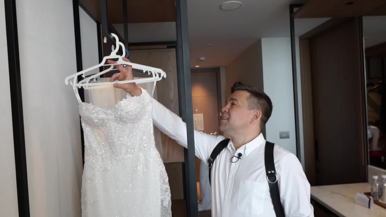 摄影师拿着婚纱告诉新娘。视频下载