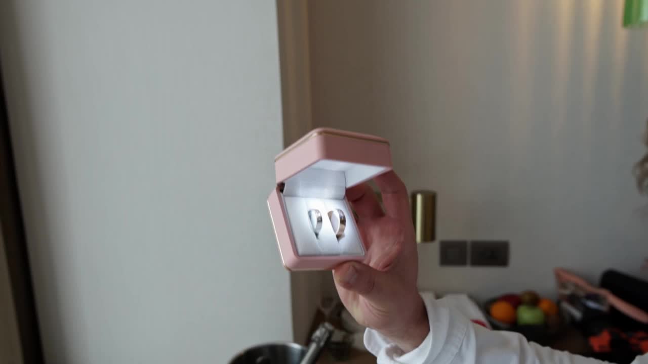 一名男子在一个有灯光的盒子里检查并展示结婚戒指。视频下载