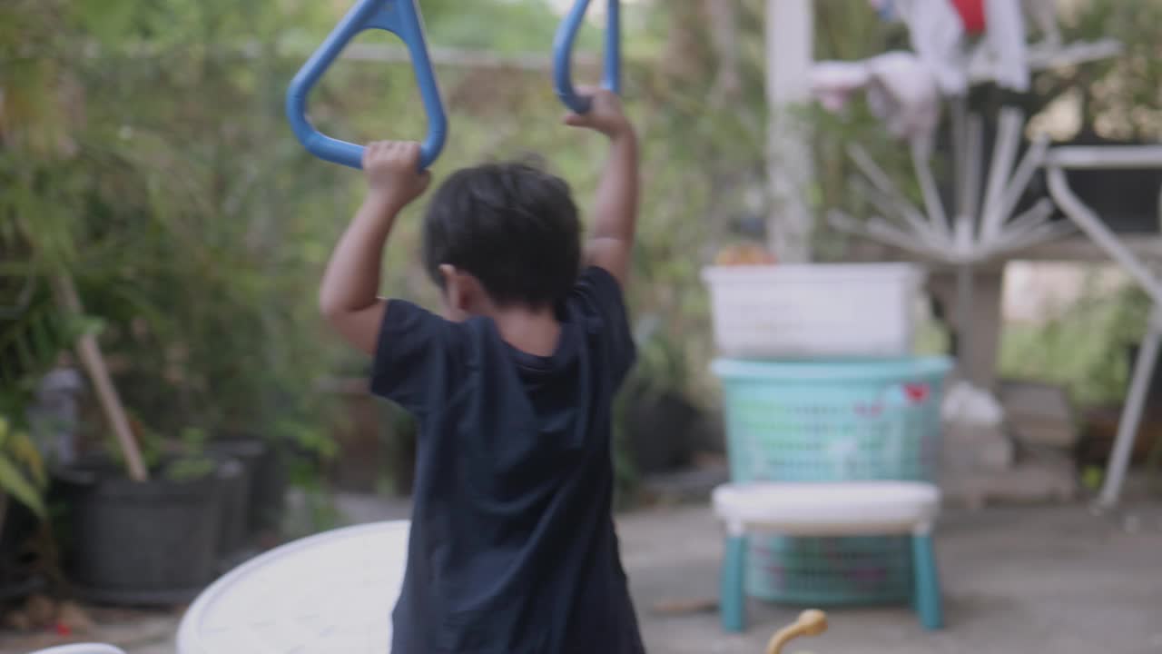 快乐的亚洲男孩在家里的绳子操场上玩耍。视频下载