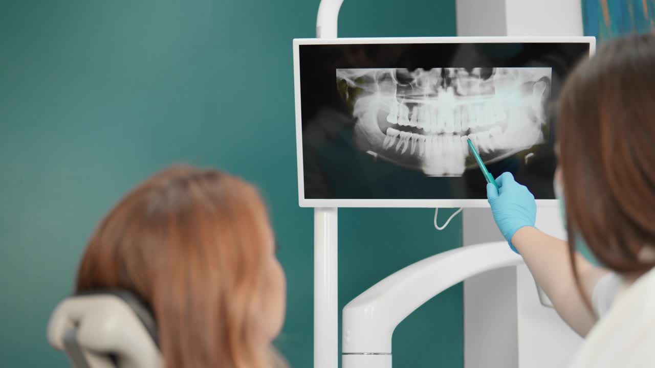牙医专业地告诉病人x光片的情况，说明所发现的病理变化，并解释纠正这些变化的必要步骤。视频下载