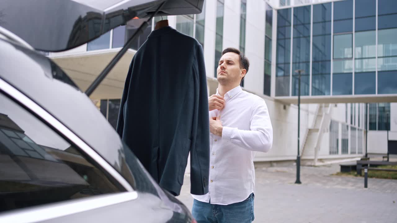 白人商人在公司大楼前穿衣服，就在他的车旁边视频下载