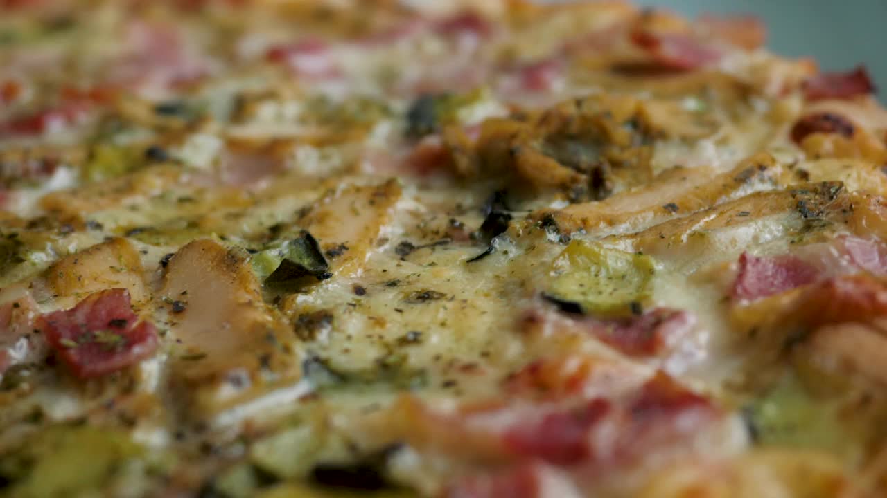 新鲜准备的披萨特写。披萨配马苏里拉芝士，培根，鸡肉，番茄，胡椒，香料，蘑菇和新鲜罗勒。火腿蘑菇自制披萨(特写)垃圾快餐。视频下载