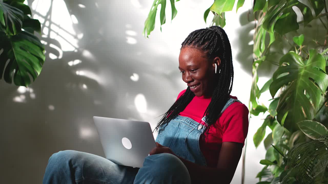 愉快的黑人学生女孩有网络摄像头交谈手势坐在舒适的共同绿化空间视频下载