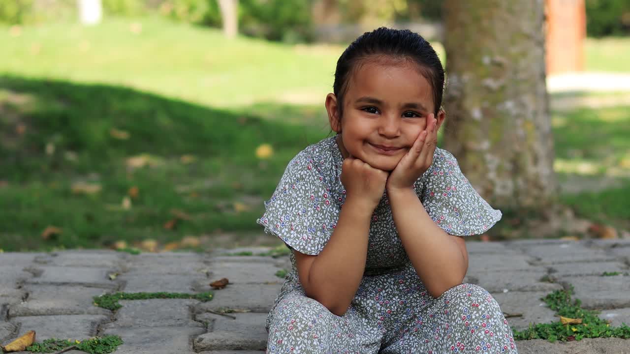 小学时代可爱的小女孩坐在户外的自然肖像视频下载