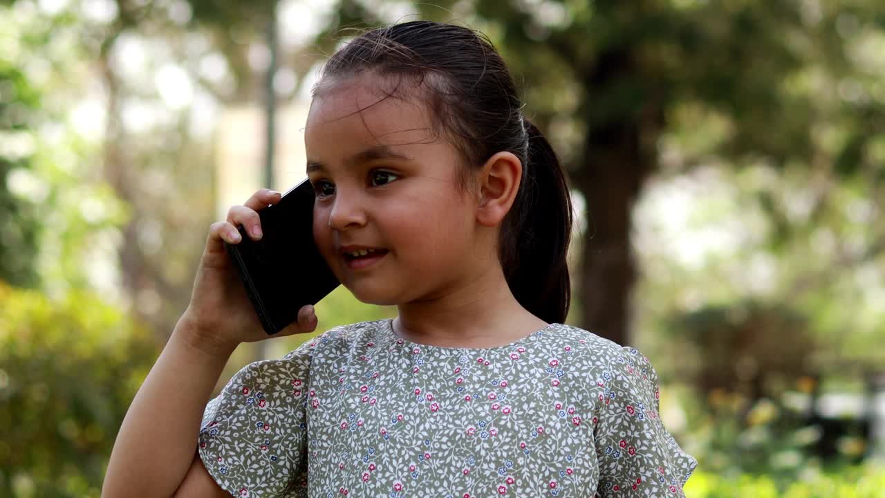 可爱的小女孩在户外用手机聊天视频肖像视频下载