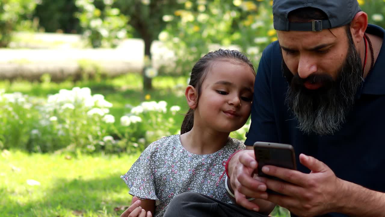 父亲和女儿一起在户外使用手机视频下载
