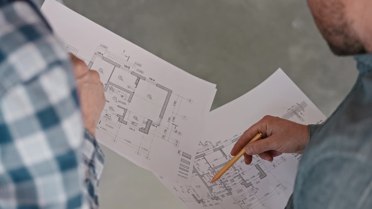 工程师和建筑工人根据详细图纸讨论房屋工程。在建筑工地工作。开发人员视频下载