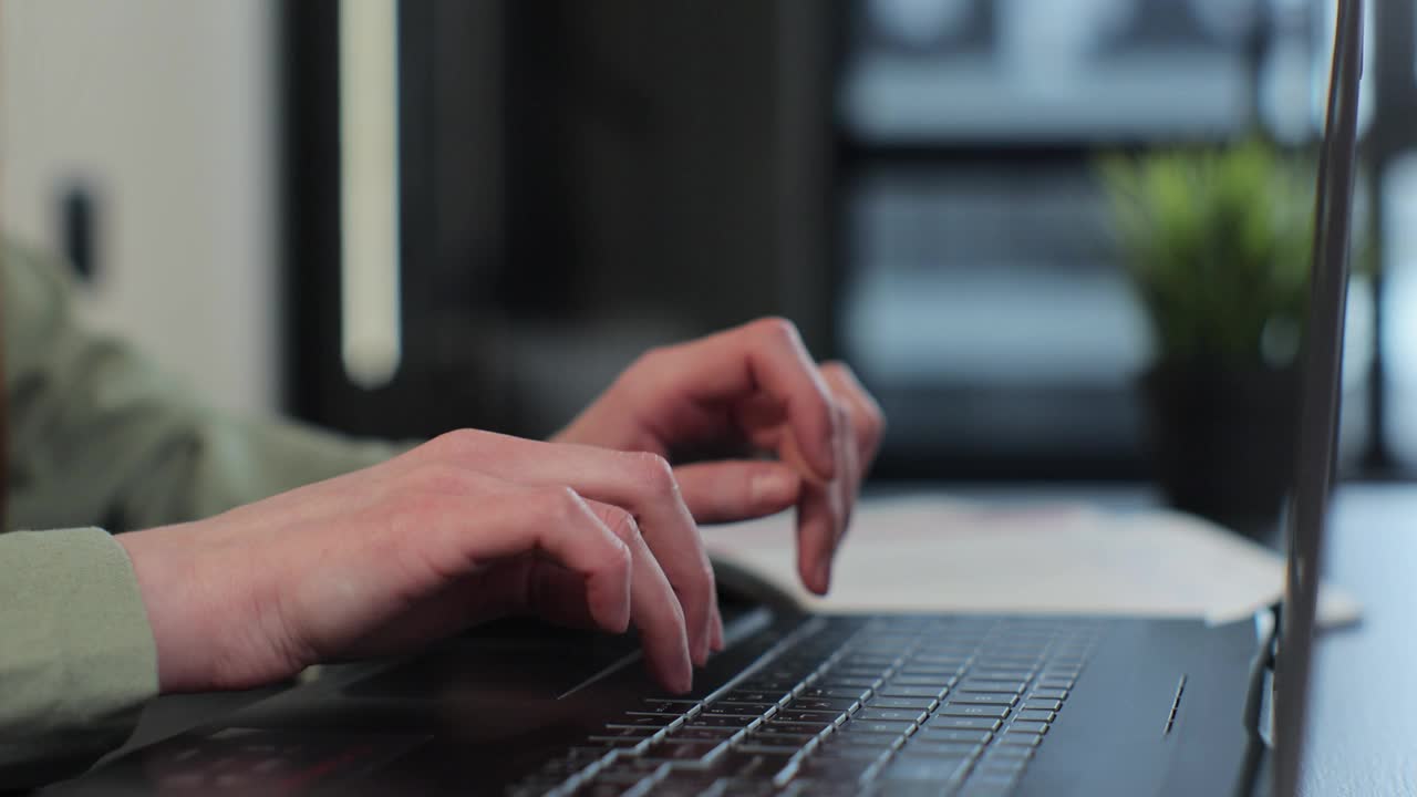 一名妇女在家里用笔记本电脑键盘打字，向专业用户示意。女性的手指在电脑上敲击和发短信，上网浏览。视频下载