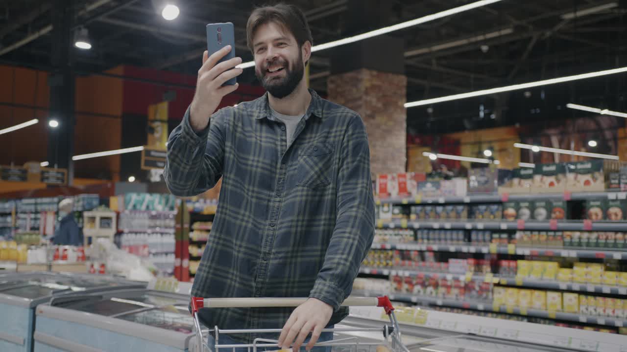 快乐的家伙在超市购物，用智能手机进行在线视频通话，讨论食物视频下载