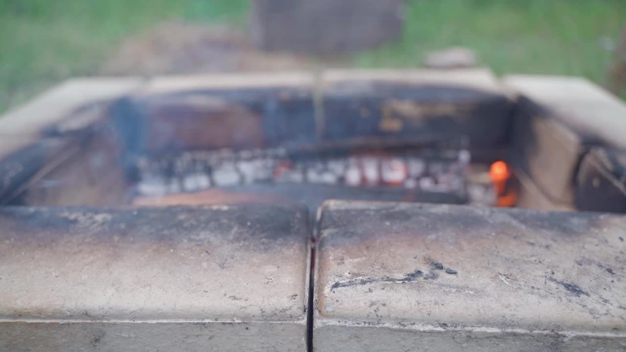 背景是燃烧的木头的耐火砖烤架。野外篝火的模糊背景视频素材