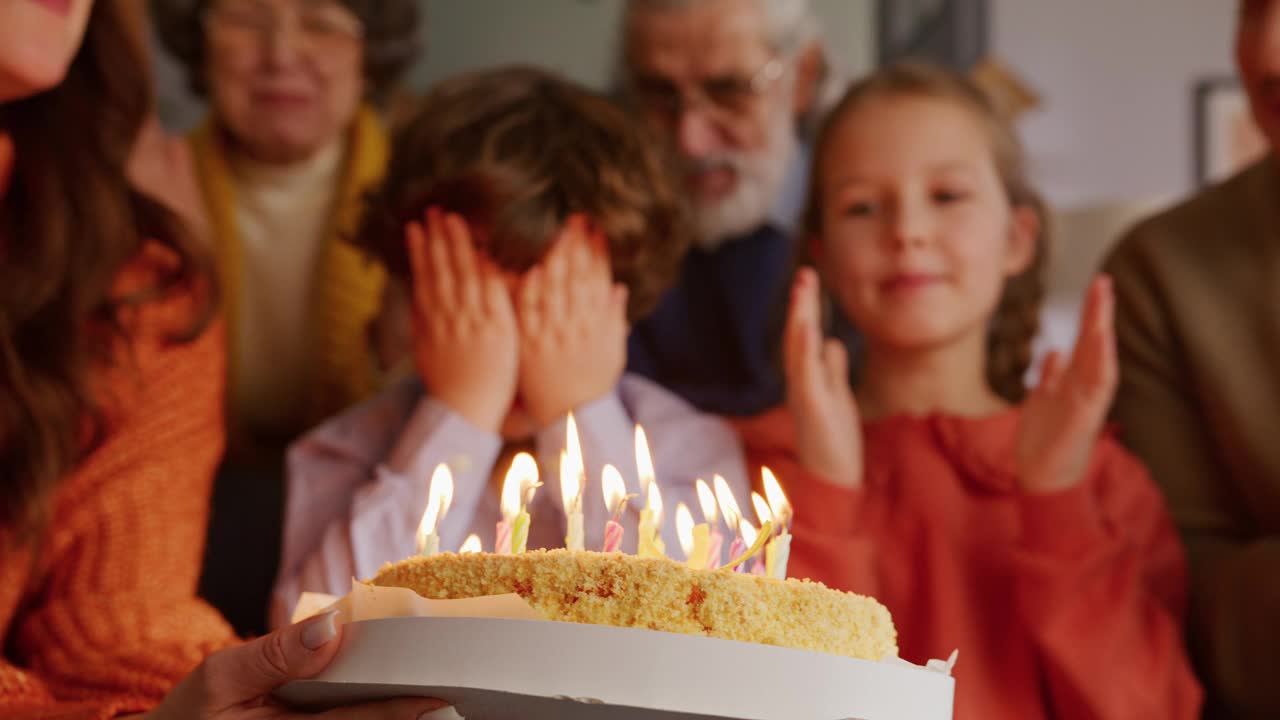 孩子用手掌遮住脸，把蜡烛吹到蛋糕上视频下载