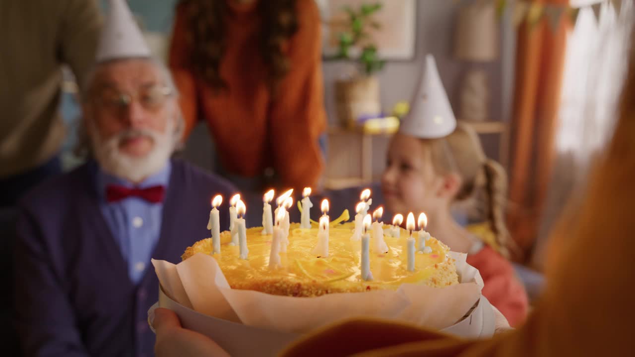 年长的男性吹着生日蛋糕上燃烧的蜡烛视频下载