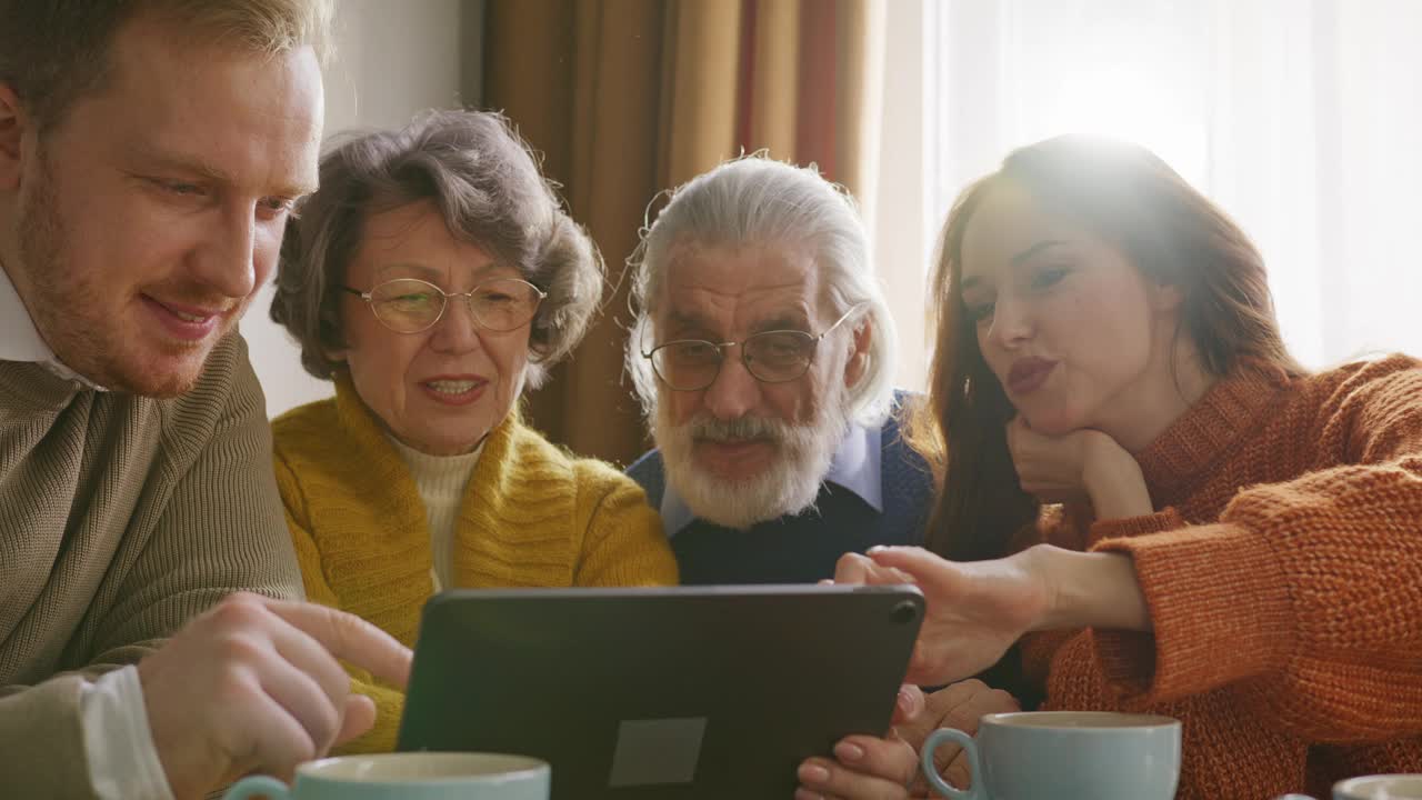 一对夫妇向老年男女展示平板电脑屏幕视频下载