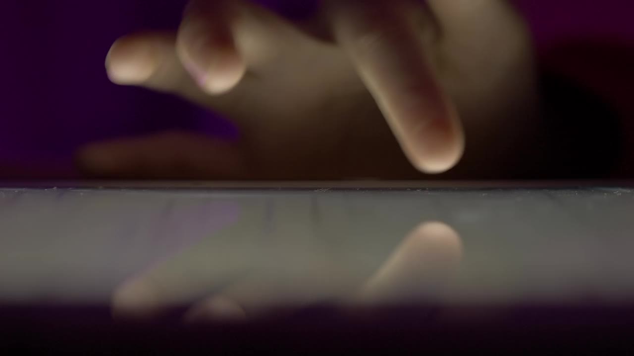 女孩在晚上用手指浏览数码平板电脑。使用智能手机，浏览社交网络的人。近距离手指滚动社交媒体应用程序或阅读新闻动态在线。视频下载