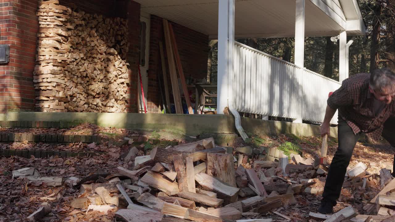 柴火分裂。秋天，成熟的伐木工在院子里准备过冬的柴火视频素材