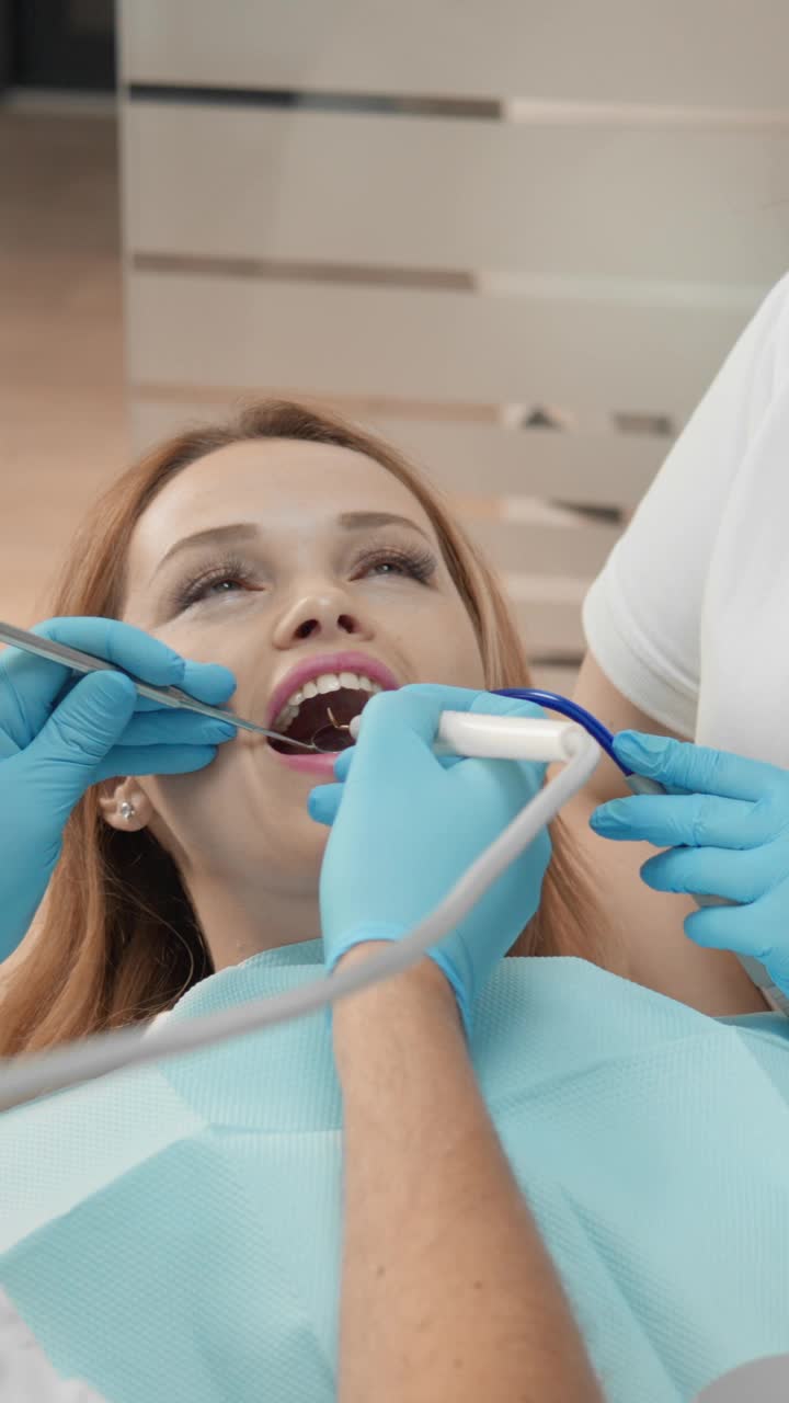 牙医与助手在牙科椅上和谐工作，为患者提供高质量、无痛的牙科治疗。视频下载