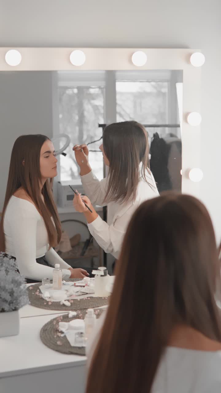 垂直视频在美容院美容师服务客户。视频记录了纠正和小心地在眉毛上化妆的过程，在自然和精致之间创造了微妙的和谐。视频下载