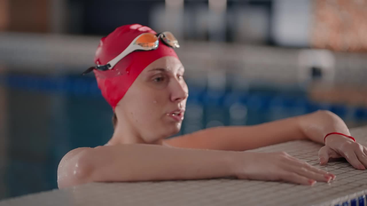 游泳后在游泳池水中休息的年轻成年女子，女运动员的肖像视频下载
