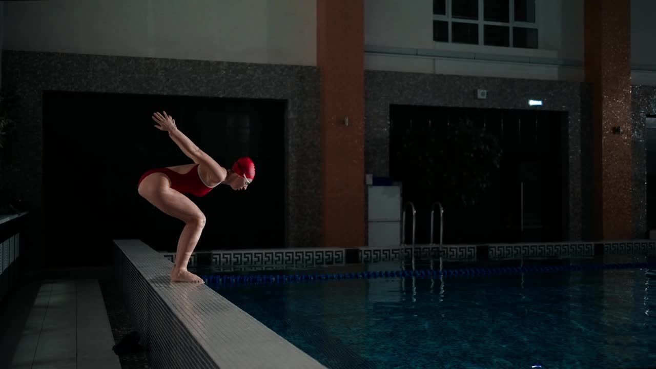 女子在游泳池训练，身穿红色泳装的女运动员侧视图视频下载