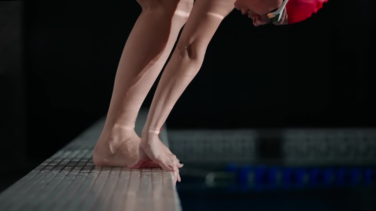 职业女游泳运动员在红色泳衣开始游泳在游泳池，腿的特写视图视频下载