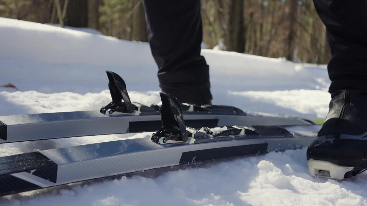 特写镜头中，一名男性滑雪者将滑雪靴扣入越野滑雪扣件中。视频下载