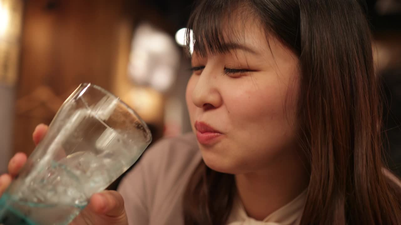年轻的女商人下班后在日本居酒屋吃着“Gyi-suji”牛肉串，喝着酒——三集之三视频下载