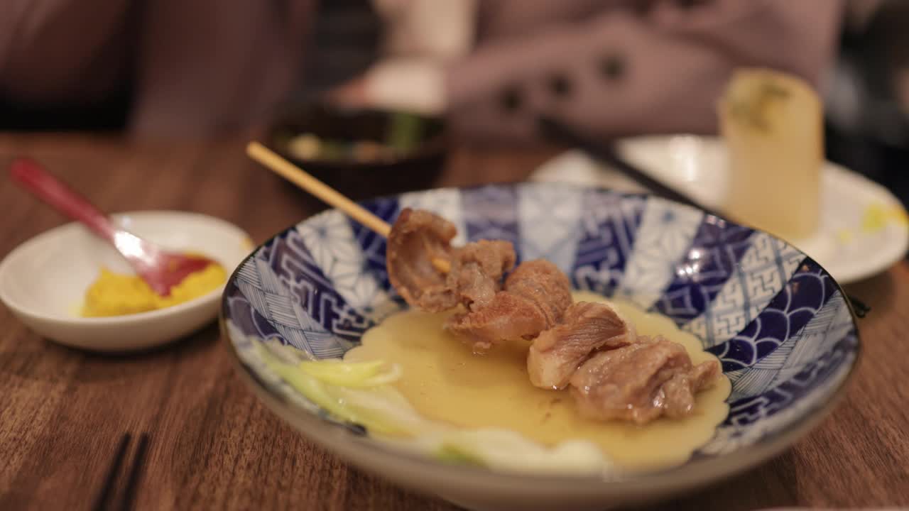 年轻女商人下班后在日本居酒屋吃着“Gyi-suji”牛肉串，喝着酒(三集之一)视频下载