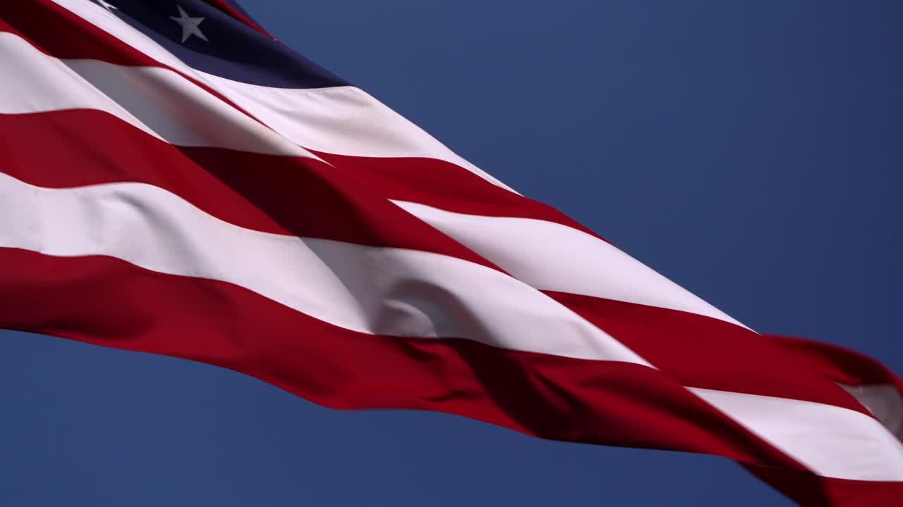 低角度近景，一面美国国旗在风中飘动，边缘残破视频下载