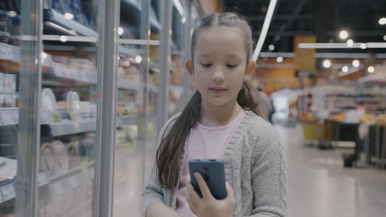 快乐的孩子用智能手机在线视频通话，讨论超市的食物视频下载
