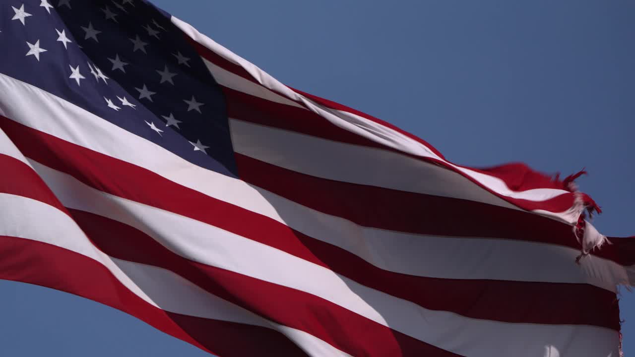 在一个阳光明媚的日子里，一面美国国旗以慢动作挥舞着。视频下载