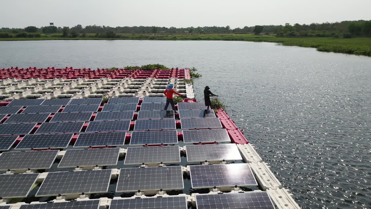 工作和维护浮动太阳能电池板或浮动光伏发电的团队。鸟瞰图。太阳能电站排阵列的水上安装系统安装在湖中。视频素材