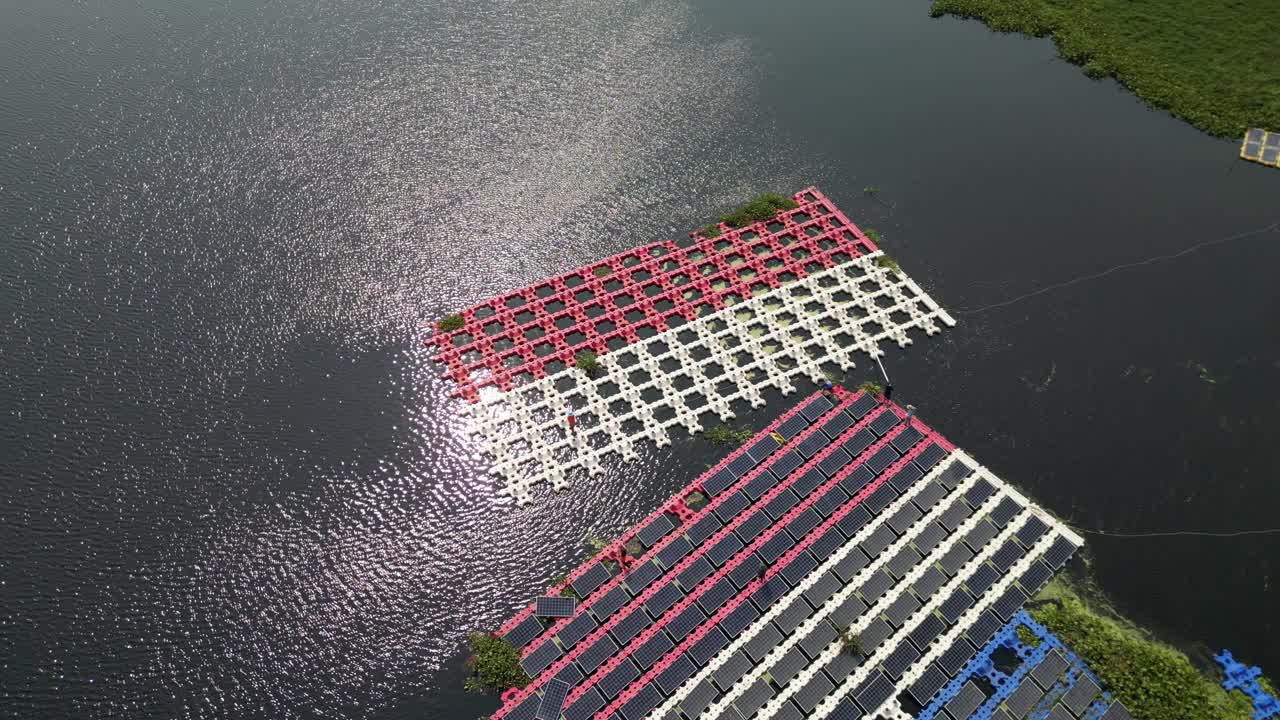 工作和维护浮动太阳能电池板或浮动光伏发电的团队。鸟瞰图。太阳能电站排阵列的水上安装系统安装在湖中。视频下载