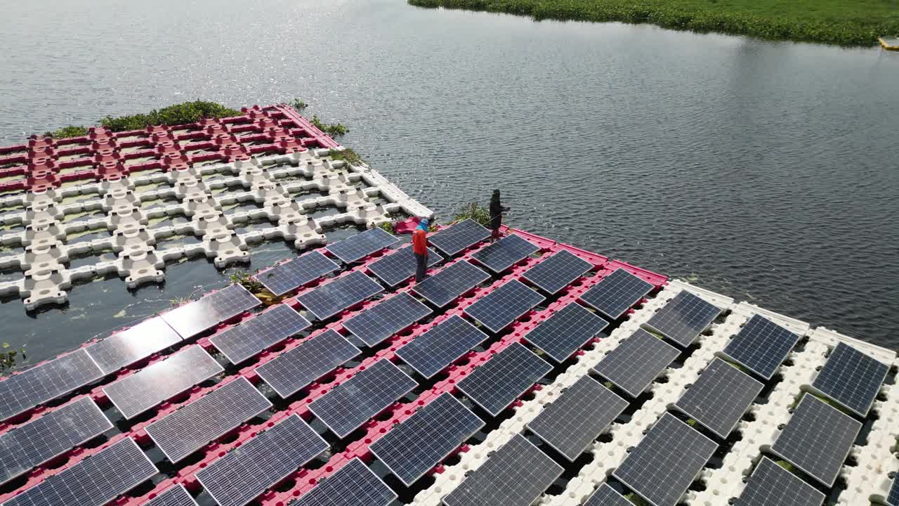 工作和维护浮动太阳能电池板或浮动光伏发电的团队。鸟瞰图。太阳能电站排阵列的水上安装系统安装在湖中。视频素材