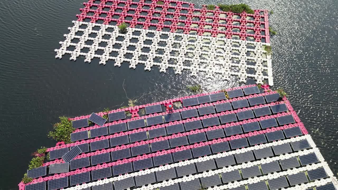 工作和维护浮动太阳能电池板或浮动光伏发电的团队。鸟瞰图。太阳能电站排阵列的水上安装系统安装在湖中。视频下载