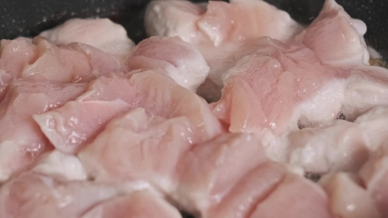 在家庭厨房里，一块块鸡肉在煎锅里煎视频下载