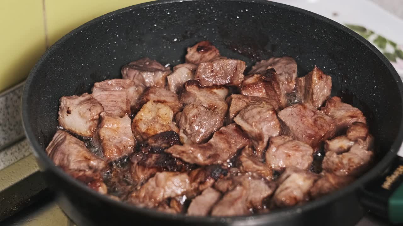 在家庭厨房里，一块块猪肉在煎锅里煎着视频下载