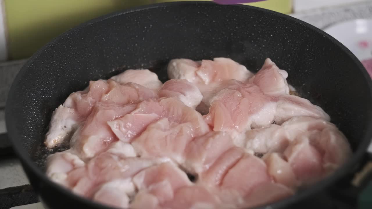 在家庭厨房里，一块块鸡肉在煎锅里煎视频下载