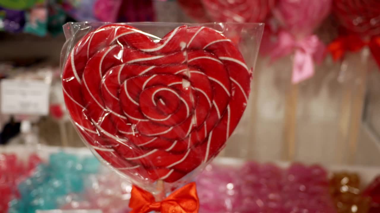 商店橱窗背景上的红色心形棒棒糖包装。情人节的概念。视频下载