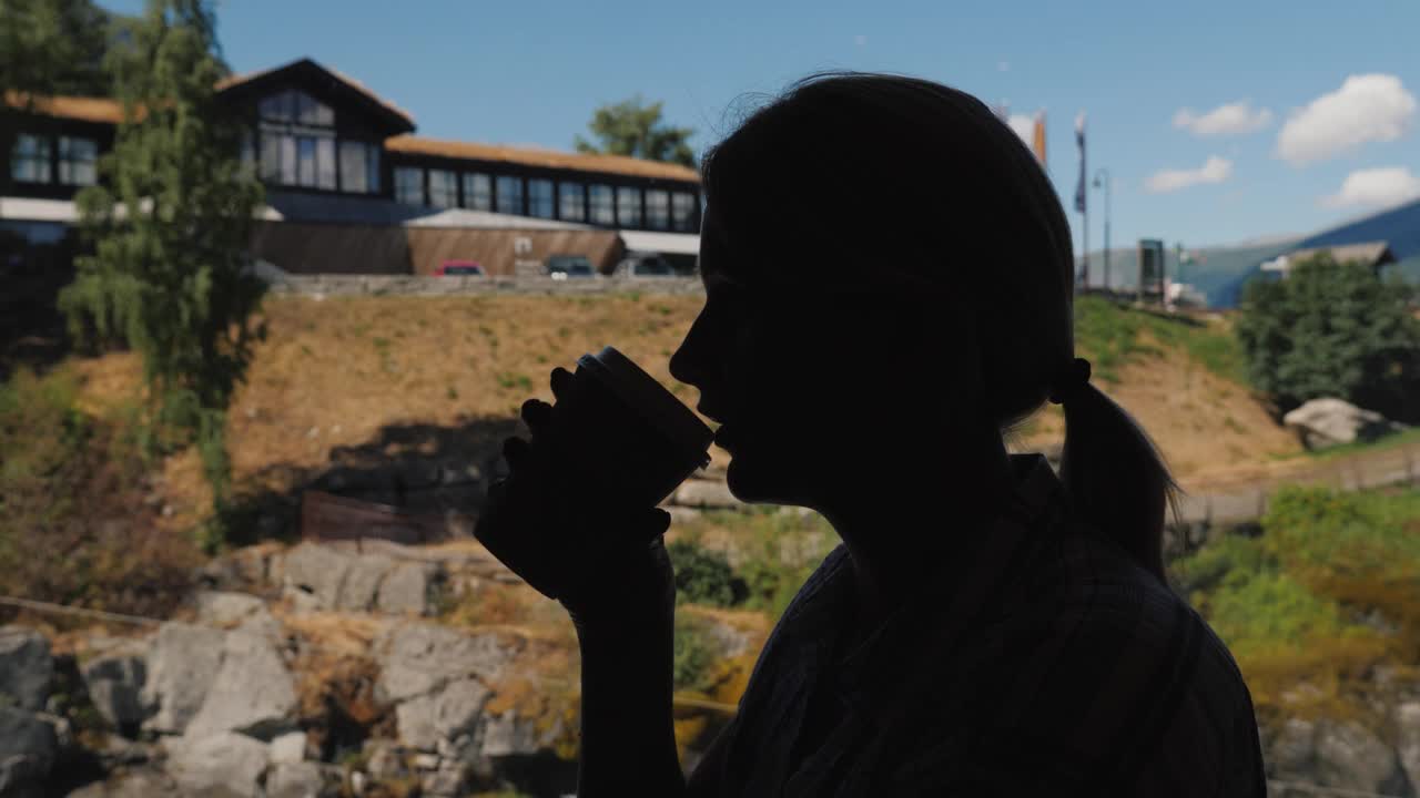 一个女人在窗边喝咖啡。坐在挪威高山上的咖啡馆里视频下载