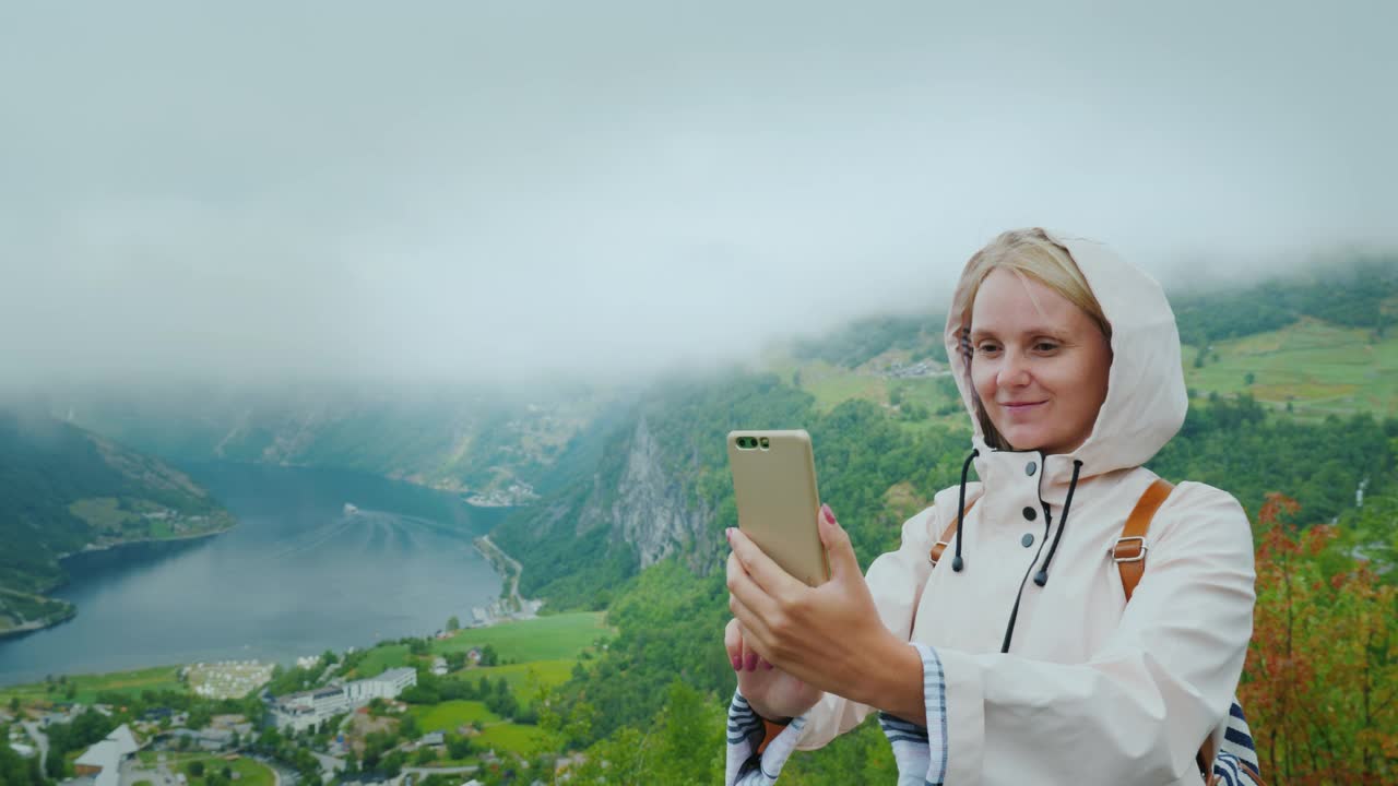 一个快乐的游客在挪威风景如画的峡湾背景下拍照。这是一个很受欢迎的摄影对象——飞崖视频下载